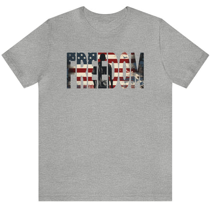 Grey Freedom USA Flag tee, which embodies the spirit of liberty and individualism. An American flag is outlined in the word 'Freedom' with a young man in silhouette gazing toward the stars and stripes, his back turned in reverence.