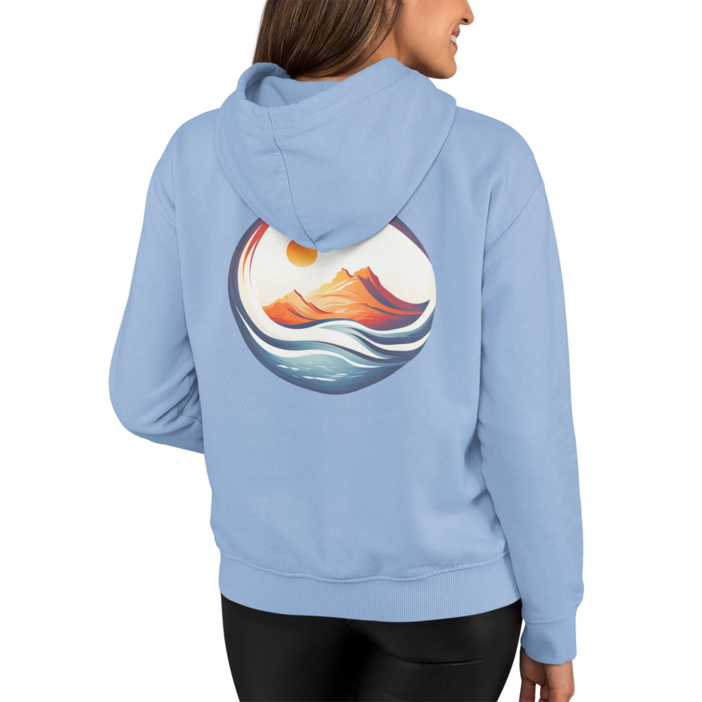 Woman wearing our light blue 'Be Free' Ocean Waves Hoodie showing a full back graphic of ocean waves around a mountain glowing in the sun.