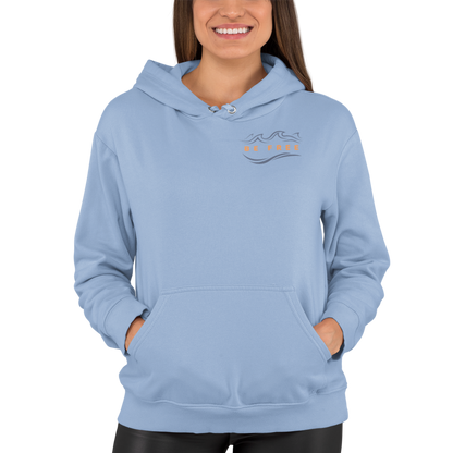 Woman wearing our light blue 'Be Free' Ocean Waves Hoodie showing the front logo with an ocean wave above the words 'Be Free' in an orange hue that matches the hoodie's full back graphic.