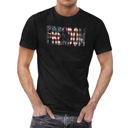 Man wearing our black Freedom USA Flag tee, which embodies the spirit of liberty and individualism. An American flag is outlined in the word 'Freedom' with a young man in silhouette gazing toward the stars and stripes, his back turned in reverence. 