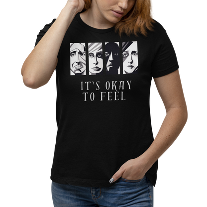 Woman wearing black mental health awareness t-shirt with four faces arranged horizontally across the shirt with the phrase 'It's Okay to Feel' below. Each face represents real emotions. Perfect for mental health advocates.