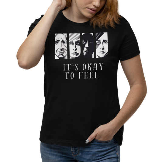 Woman wearing black mental health awareness t-shirt with four faces arranged horizontally across the shirt with the phrase 'It's Okay to Feel' below. Each face represents real emotions. Perfect for mental health advocates.