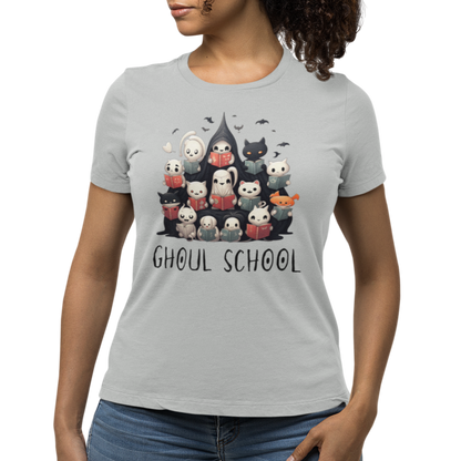 Woman wearing a grey Halloween 'Ghoul School' ghost t-shirt featuring a full graphic with cute ghosts reading books to create a spooky classroom scene. The caption 'Ghoul School' appears in spooky font. Unique t-shirt perfect for teachers, librarians, students, or anyone wanting to show off their Halloween school spirit. 