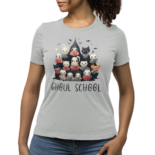 Woman wearing a grey Halloween 'Ghoul School' ghost t-shirt featuring a full graphic with cute ghosts reading books to create a spooky classroom scene. The caption 'Ghoul School' appears in spooky font. Unique t-shirt perfect for teachers, librarians, students, or anyone wanting to show off their Halloween school spirit. 